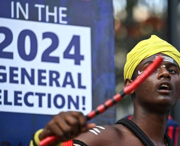 Un artiste vêtu d’un costume traditionnel, devant un panneau électoral, au Karnataka, en Inde. Le Premier ministre nationaliste hindou Narendra Modi est fortement pressenti pour remporter un troisième mandat lors de cette campagne qui débutera le 19 avril. | AFP/IDREES MOHAMMED